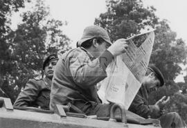 Militar a ler jornal em cima de um tanque