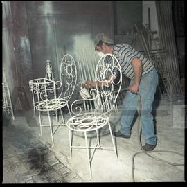 Homem a pintar móveis de ferro