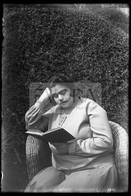 Maria Noémia lendo um livro no jardim
