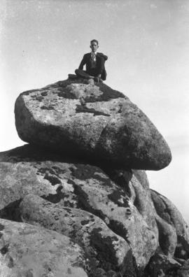 Rapaz sentado em grandes pedras